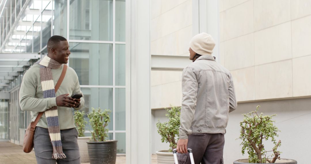 Multiethnic men chatting while commuting with suitcase outside modern office complex