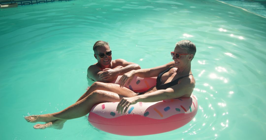 Senior Couple Enjoying Relaxation on a Sunny Pool Day with Inflatable Float
