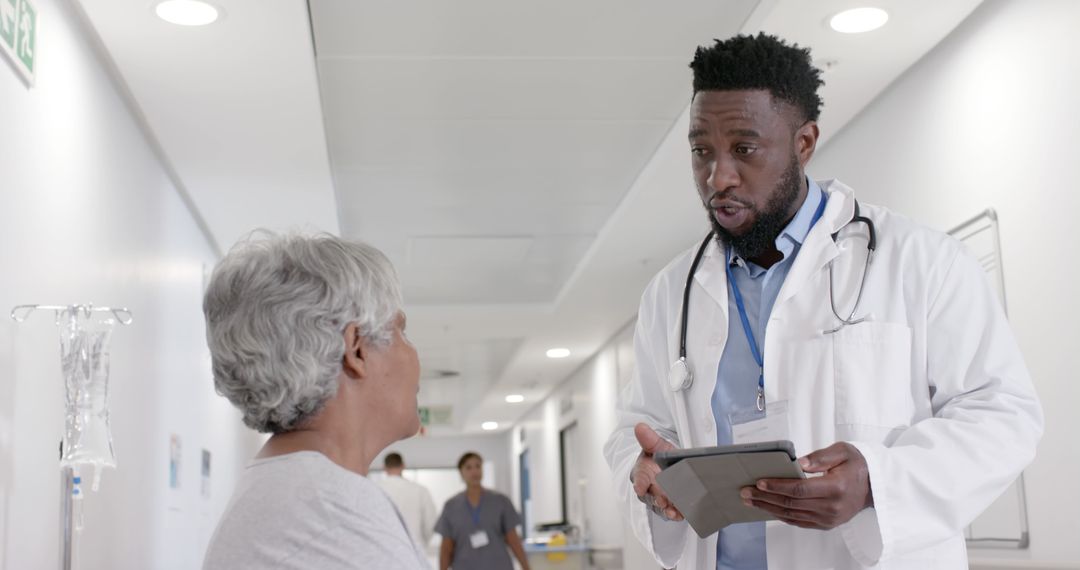 Doctor Discussing Medical Information with Elderly Patient in Hospital Hallway - Free Images, Stock Photos and Pictures on Pikwizard.com