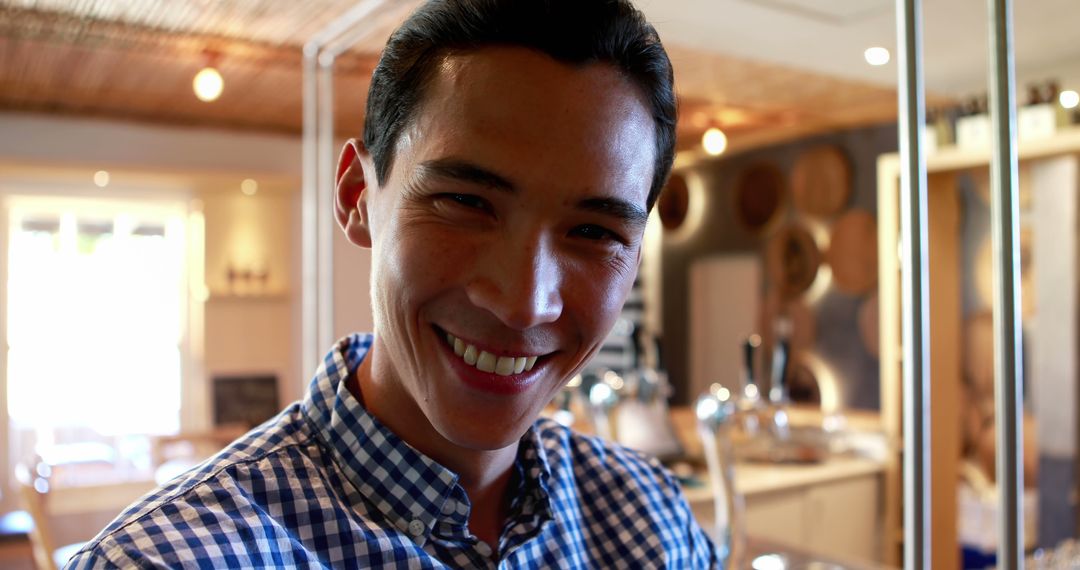 Smiling Young Man in Checkered Shirt Indoors Brightly Lit Room - Free Images, Stock Photos and Pictures on Pikwizard.com