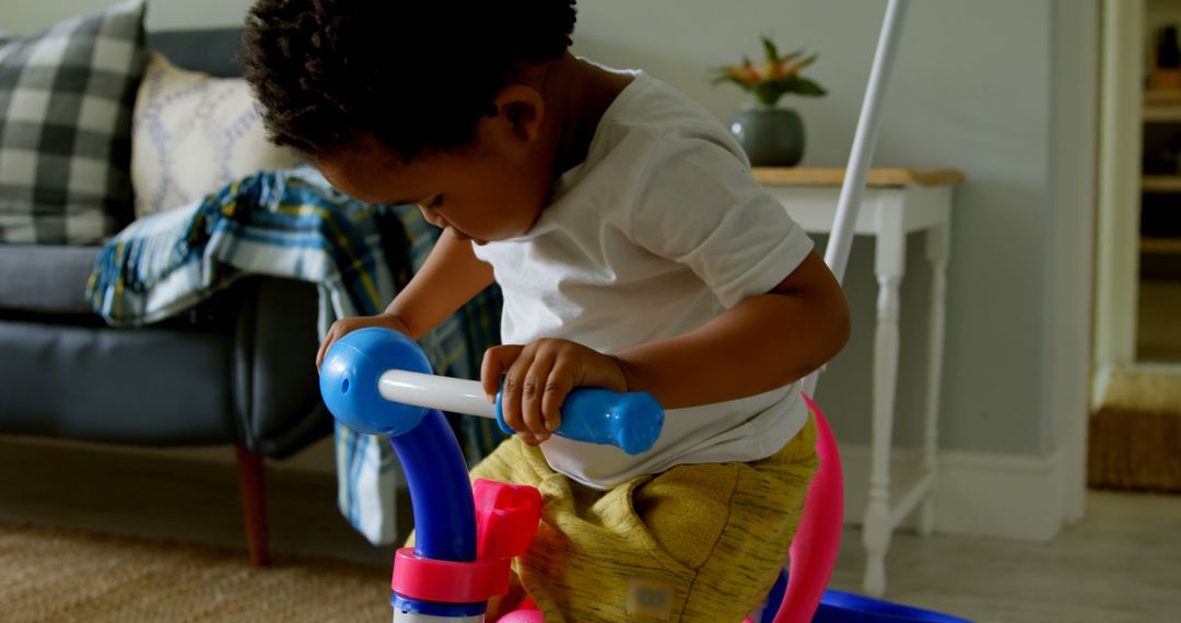 Curious Toddler Playing on Colorful Tricycle Indoors - Free Images, Stock Photos and Pictures on Pikwizard.com