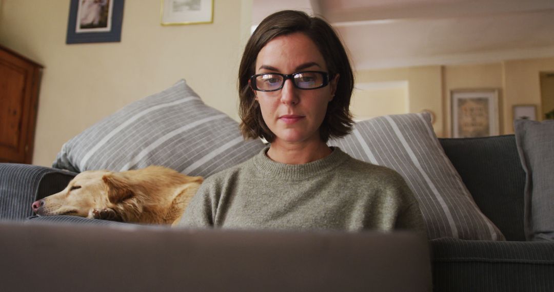 Woman working from home on laptop with dog resting on couch - Free Images, Stock Photos and Pictures on Pikwizard.com