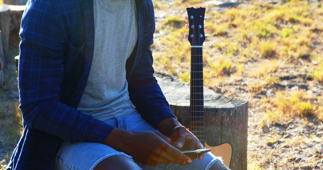 Musician Relaxing Outdoors with Acoustic Guitar - Free Images, Stock Photos and Pictures on Pikwizard.com