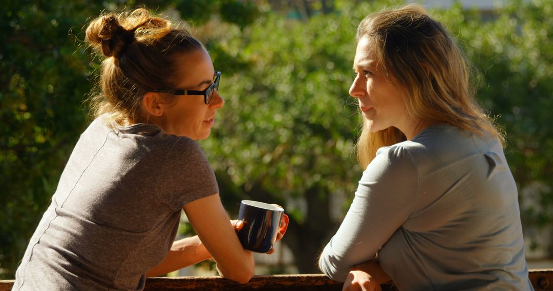 Two Women Engaging in Conversation while Drinking Coffee Outdoors - Free Images, Stock Photos and Pictures on Pikwizard.com