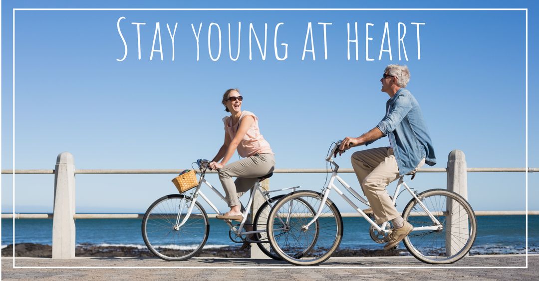 Joyful senior couple cycling by serene seaside