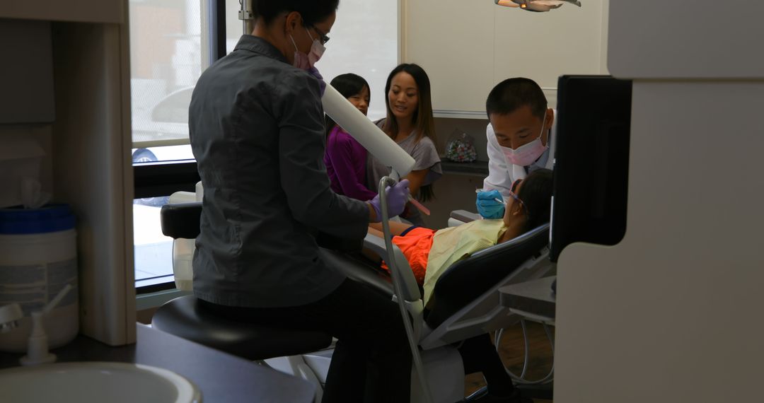 Pediatric Dentist Treating Patient with Family in Background - Free Images, Stock Photos and Pictures on Pikwizard.com