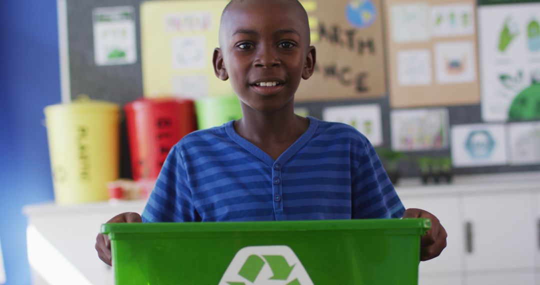Smiling Schoolboy Holding Recycling Bin in Classroom