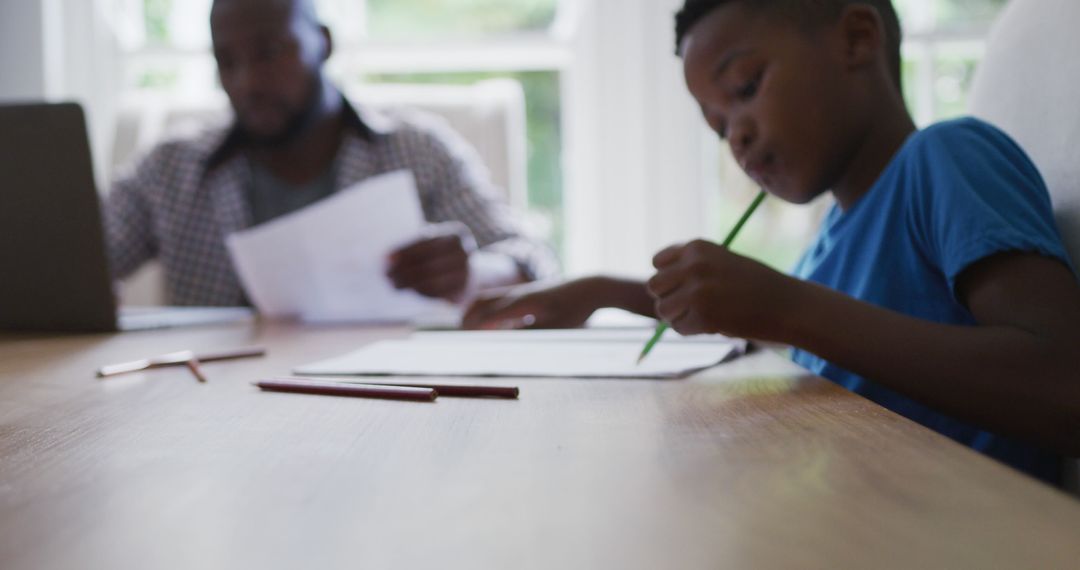 Focused African American Boy Studying While Father Works at Home - Free Images, Stock Photos and Pictures on Pikwizard.com