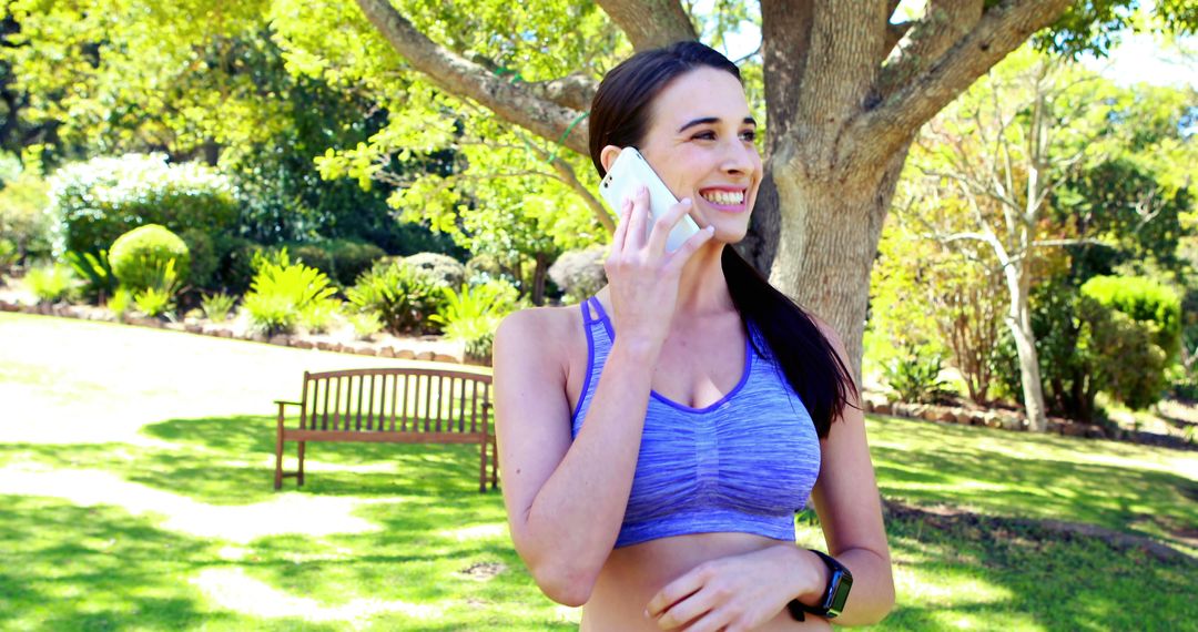 Smiling Woman in Sports Bra Talking on Phone Outdoors - Free Images, Stock Photos and Pictures on Pikwizard.com