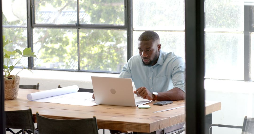 Professional Black Man Working on Laptop in Open Office Environment