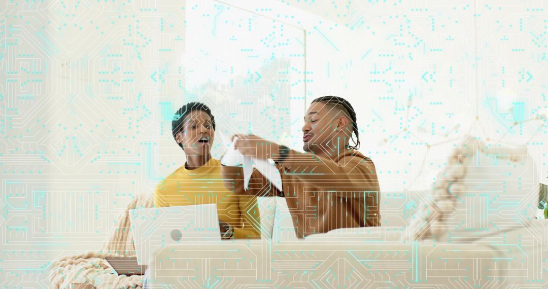 Friends reviewing torn document on sofa with laptop, cozy home collaboration and tech overlay