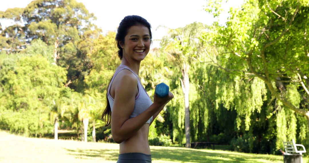 Happy Woman Exercising with Dumbbells in Park - Free Images, Stock Photos and Pictures on Pikwizard.com