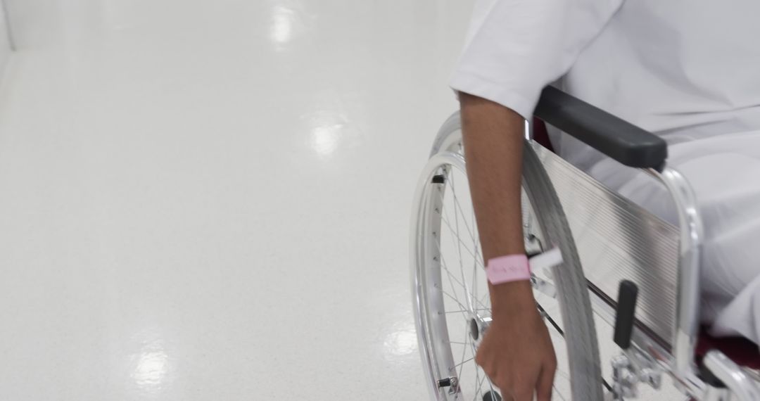 Person wearing hospital bracelet in wheelchair in bright room - Free Images, Stock Photos and Pictures on Pikwizard.com