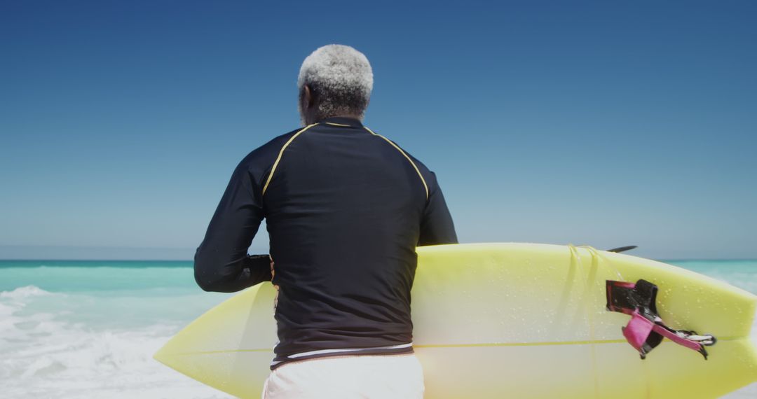 Senior man with surfboard ready to surf ocean - Free Images, Stock Photos and Pictures on Pikwizard.com