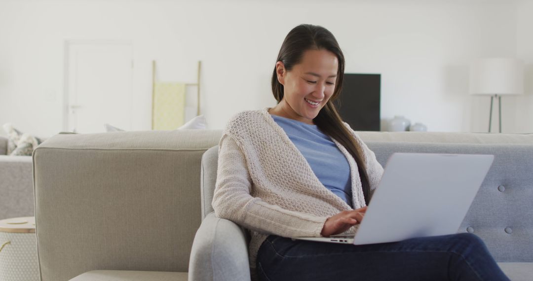 Smiling Woman Relaxing on Couch Using Laptop in Modern Living Room - Free Images, Stock Photos and Pictures on Pikwizard.com