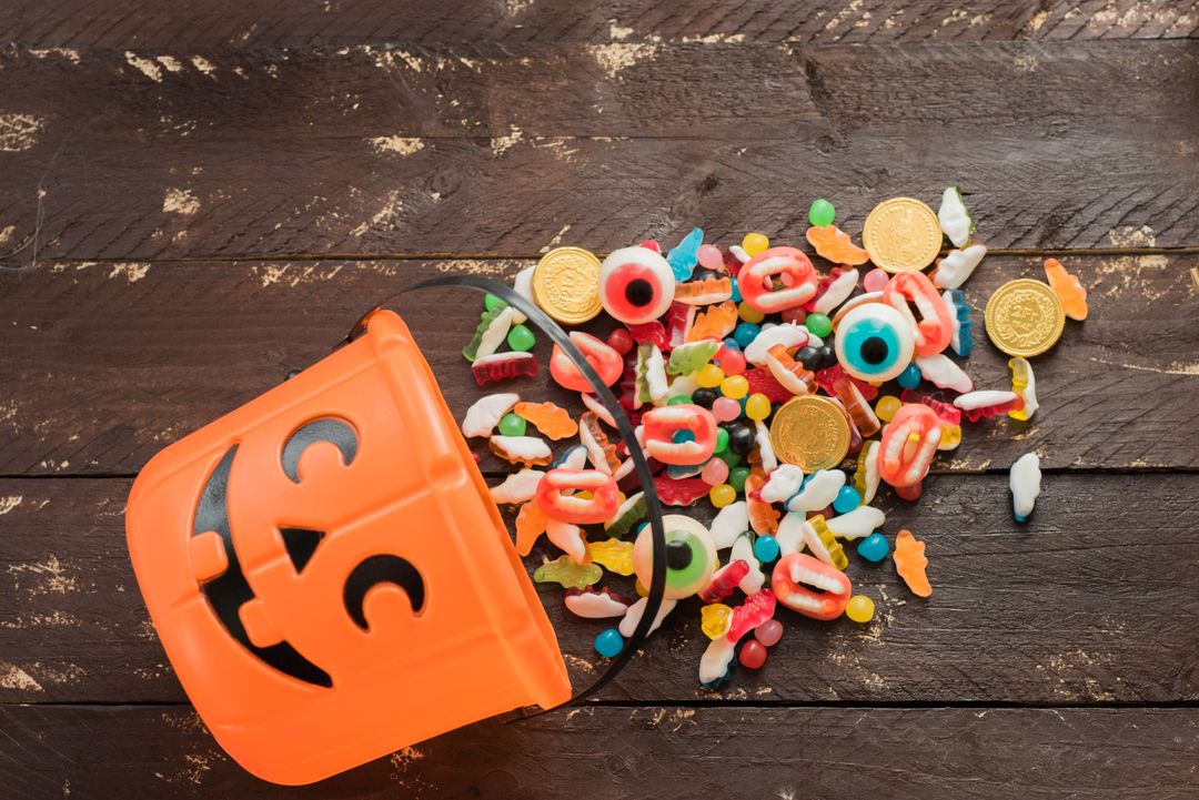 Spilled Halloween Candy and Goes with Pumpkin Bucket on Wooden Table