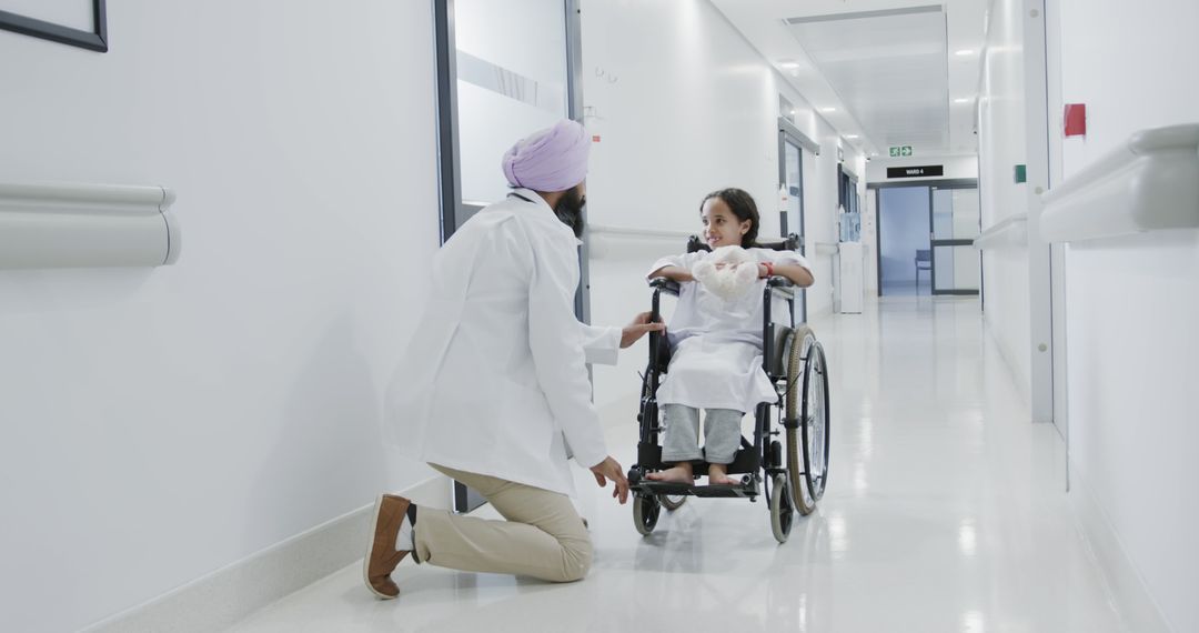 Doctor Conversing with Young Patient in Wheelchair in Hospital Corridor - Free Images, Stock Photos and Pictures on Pikwizard.com