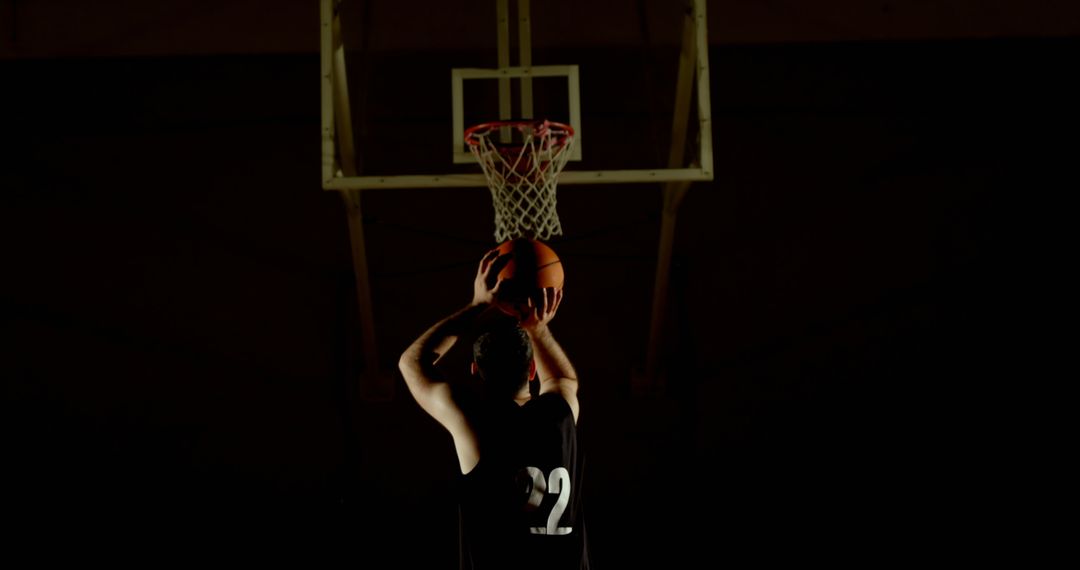 Basketball Player Shooting Ball at Hoop in Low Light - Free Images, Stock Photos and Pictures on Pikwizard.com