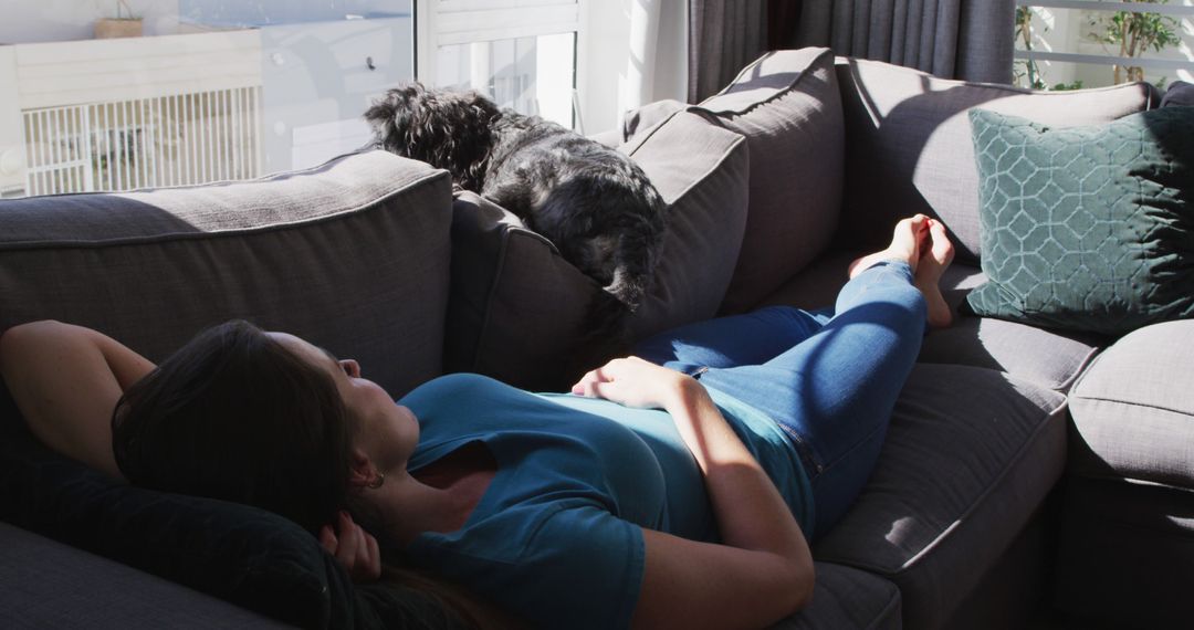 Woman Relaxing on Couch with Dog by Sunlit Window