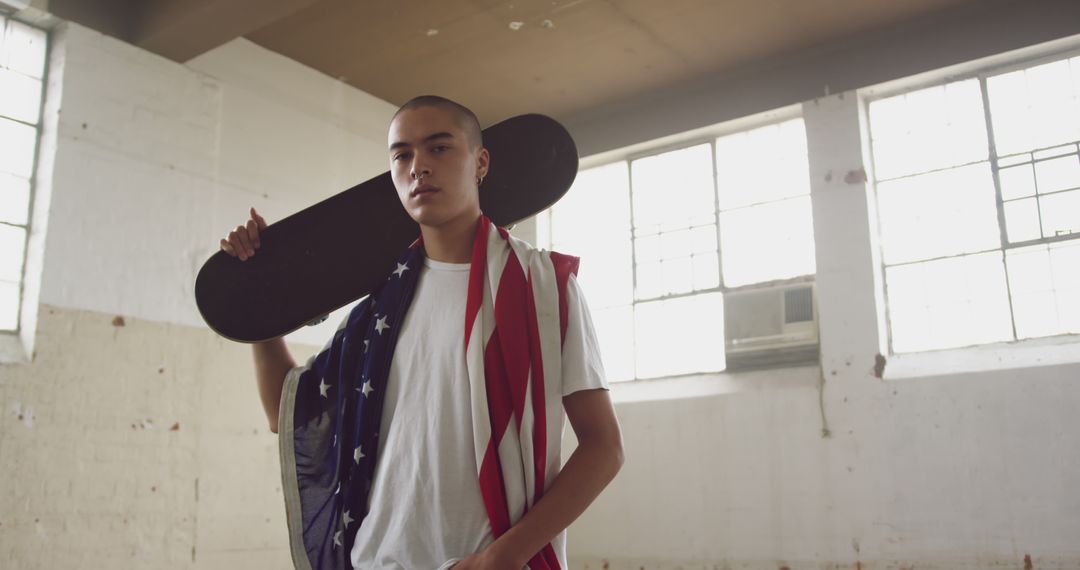 Teenage skater wearing American flag holding skateboard indoors - Free Images, Stock Photos and Pictures on Pikwizard.com