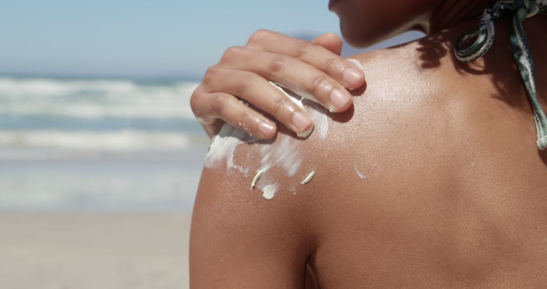 Woman Applying Sunscreen on Shoulder at Sunny Beach - Free Images, Stock Photos and Pictures on Pikwizard.com