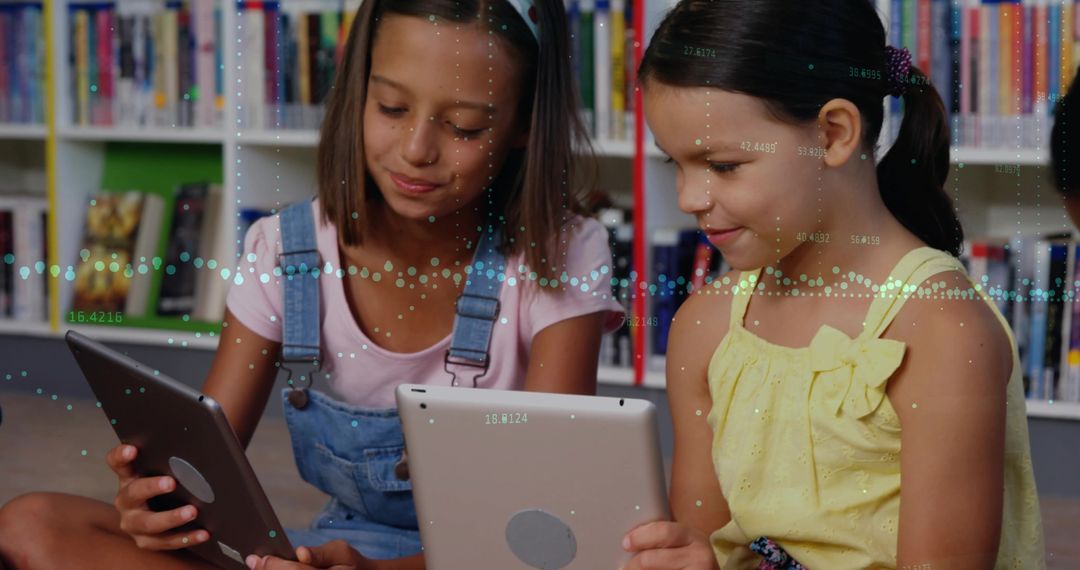 Two Girls Using Tablets on Library Carpet Reading Together and Exploring Digital Learning