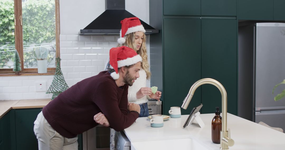 Couple Celebrating Christmas Morning in Modern Kitchen With Santa Hats - Free Images, Stock Photos and Pictures on Pikwizard.com