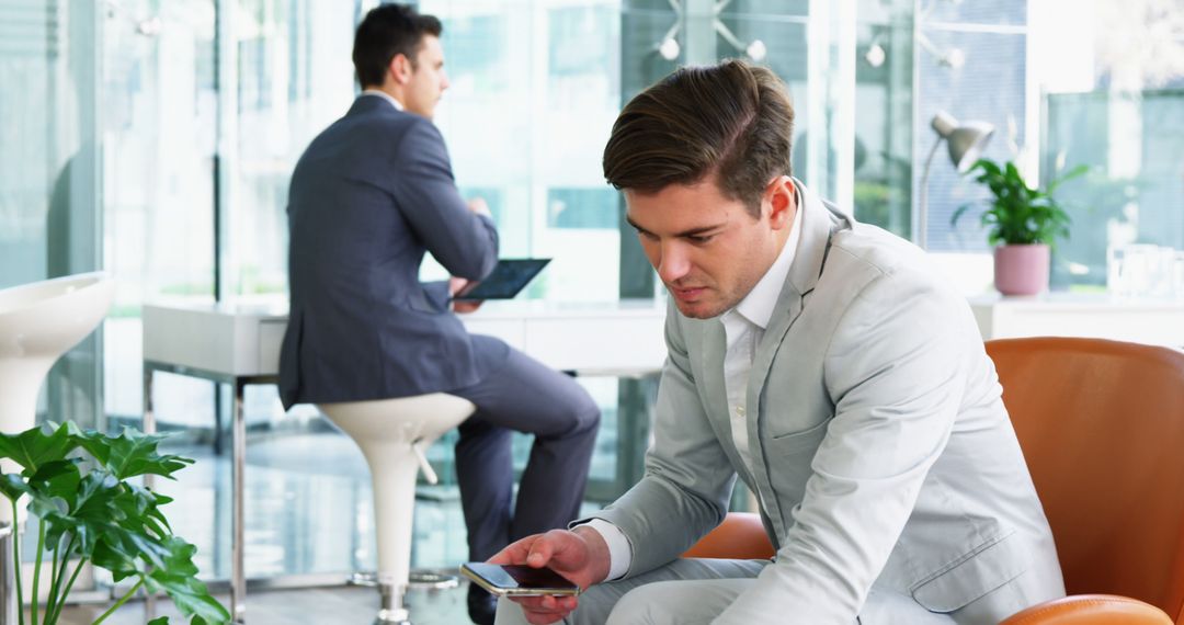 Businessman Using Smartphone in Modern Office Lounge - Free Images, Stock Photos and Pictures on Pikwizard.com