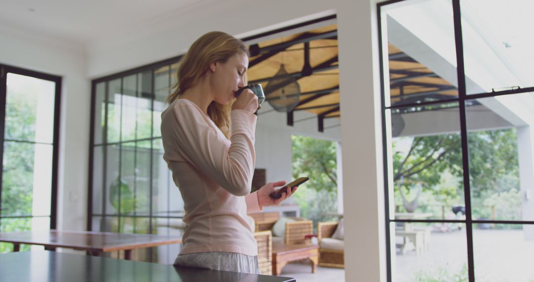 Woman Drinking Coffee and Using Smartphone in Modern Home - Free Images, Stock Photos and Pictures on Pikwizard.com