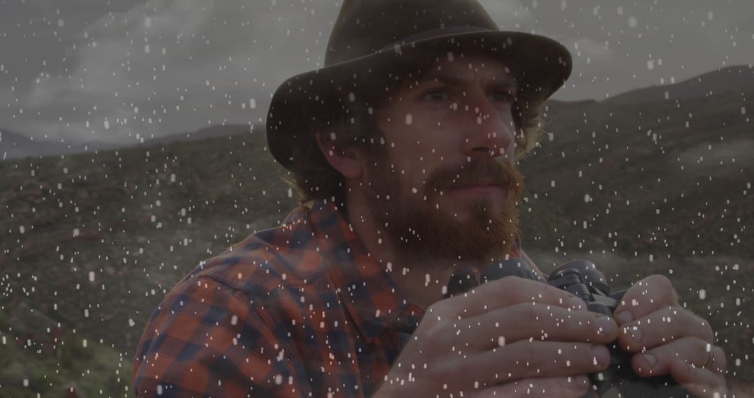 Man Using Binoculars in Snowy Mountain Landscape