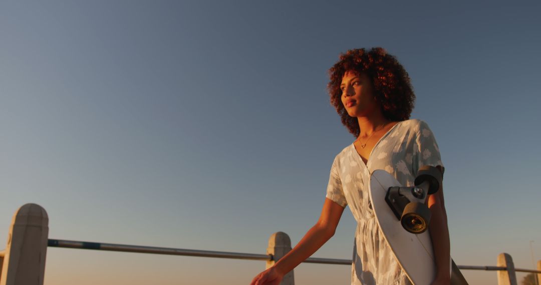 Young Woman With Curly Hair Walking at Sunset Holding Skateboard - Free Images, Stock Photos and Pictures on Pikwizard.com