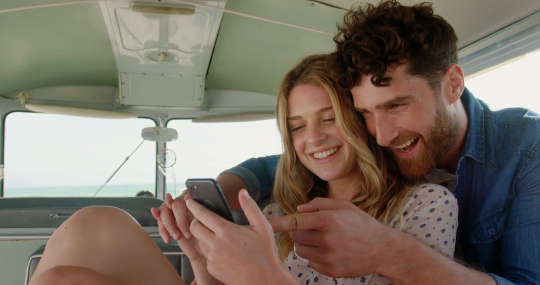 Happy Couple Smiling and Using Smartphone in Camper Van by the Beach - Free Images, Stock Photos and Pictures on Pikwizard.com