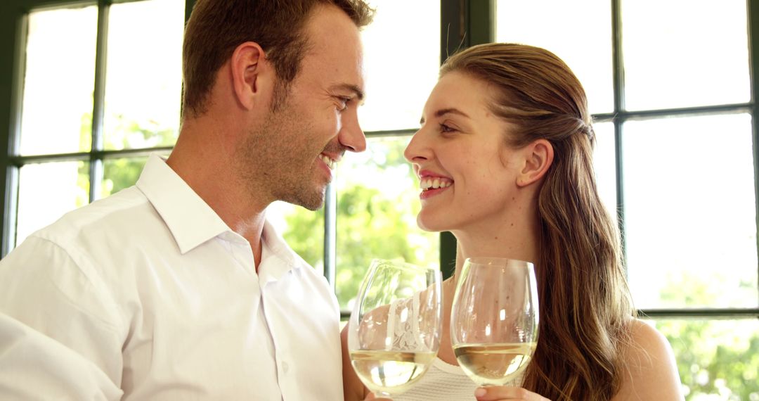 Joyful Couple Toasting with White Wine by Sunlit Window