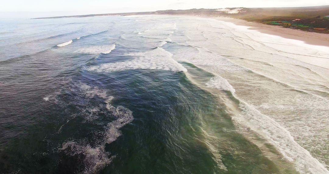 Aerial view of waves reaching a shore at beach on a sunny day 4k - Free Images, Stock Photos and Pictures on Pikwizard.com