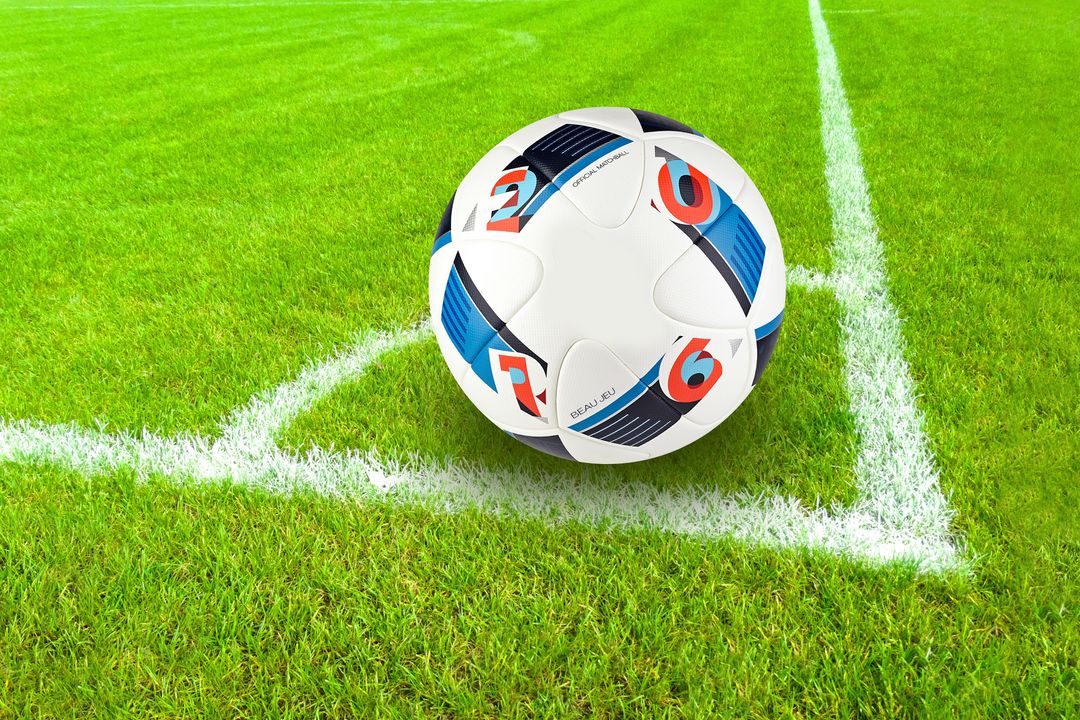 Soccer ball resting in corner on vibrant green grass with crisp white field lines