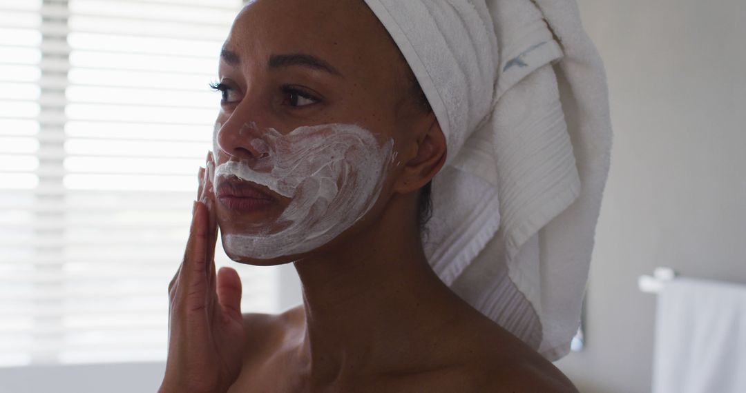 Woman Applying Face Mask with Towel Wrapped Around Hair - Free Images, Stock Photos and Pictures on Pikwizard.com