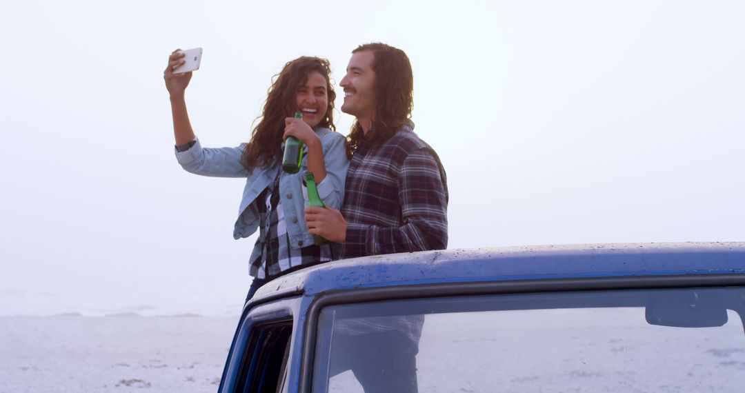 Happy Couple Taking Selfie by the Beach, Enjoying Bottled Drink - Free Images, Stock Photos and Pictures on Pikwizard.com