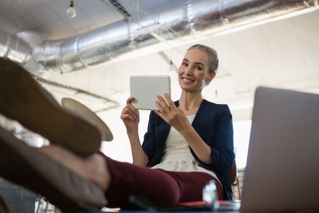 Woman Relaxing in Modern Office with Tablet Technology - Free Images, Stock Photos and Pictures on Pikwizard.com