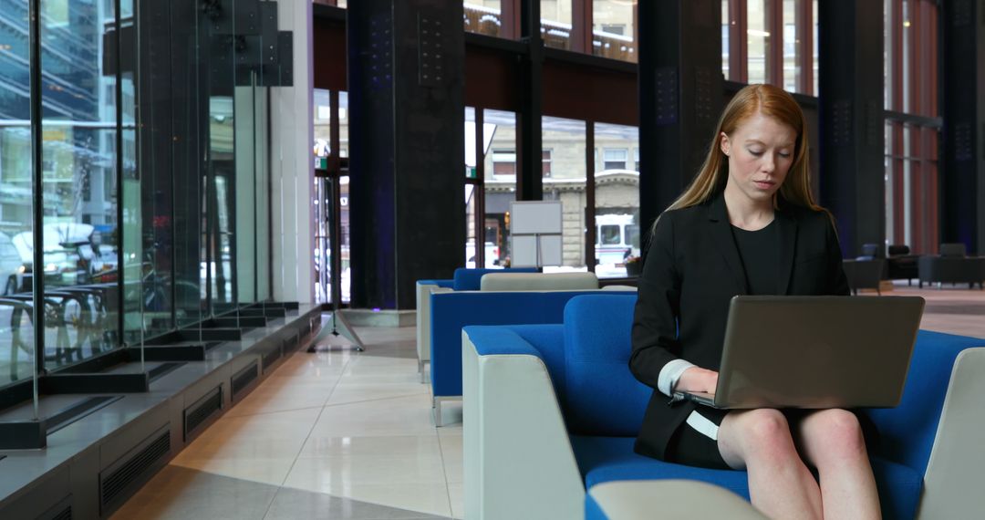 Businesswoman Working on Laptop in Modern Office Lobby - Free Images, Stock Photos and Pictures on Pikwizard.com