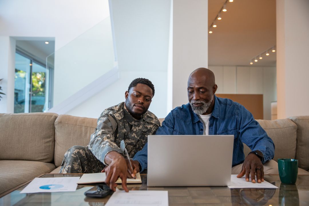 Father and Army Soldier Son Collaborating on Laptop in Modern Home