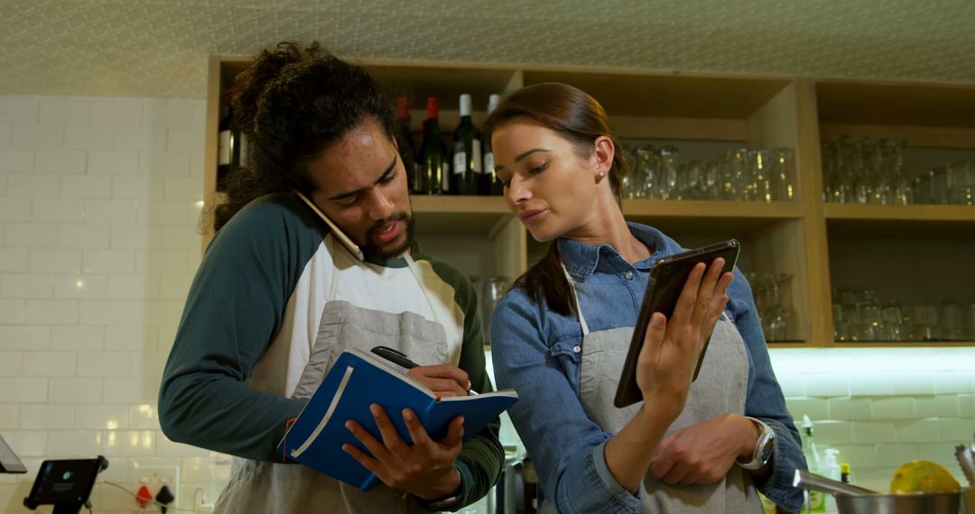 Two Chefs Collaborating with Cookbook and Tablet in Modern Kitchen