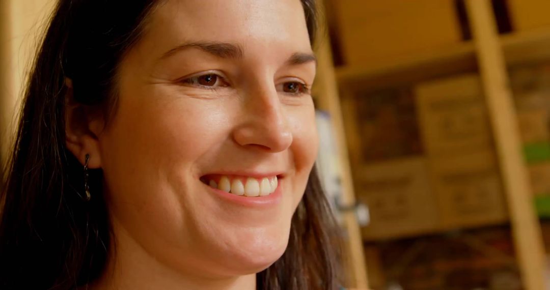 Smiling woman leaning in storeroom with wooden shelving and stacked cardboard boxes