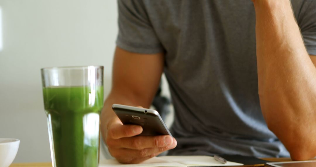 Man Drinking Green Smoothie While Using Smartphone - Free Images, Stock Photos and Pictures on Pikwizard.com