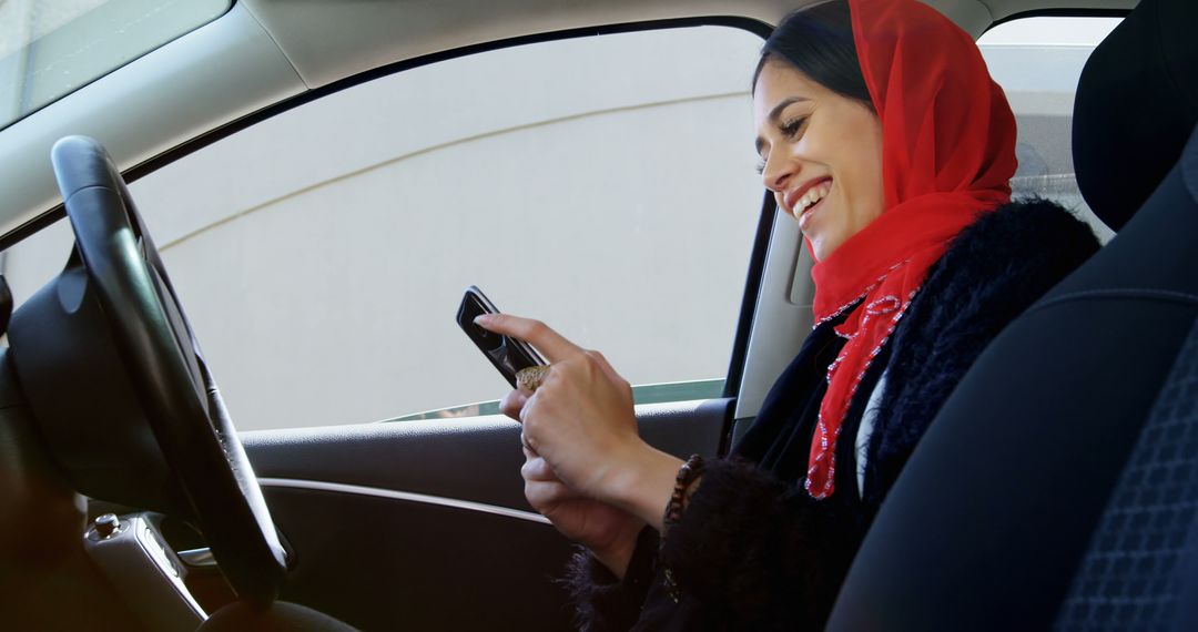 Smiling Woman in Red Scarf Using Smartphone While Seated in Car - Free Images, Stock Photos and Pictures on Pikwizard.com