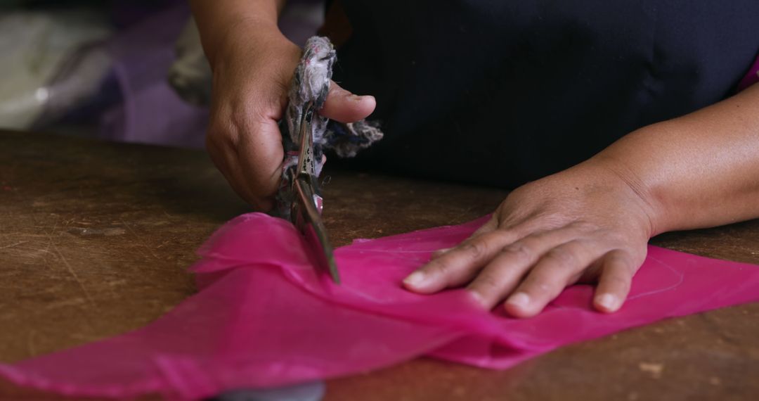 Tailor Cutting Pink Fabric with Scissors on Wooden Table - Free Images, Stock Photos and Pictures on Pikwizard.com