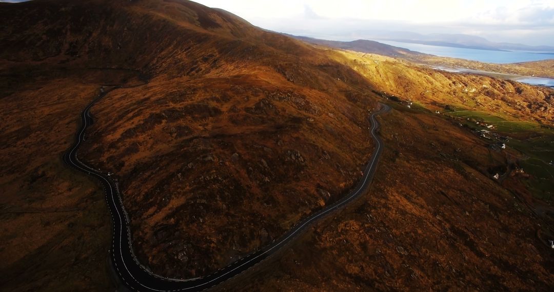 Winding Mountain Road Through Rugged Terrain at Sunset - Free Images, Stock Photos and Pictures on Pikwizard.com