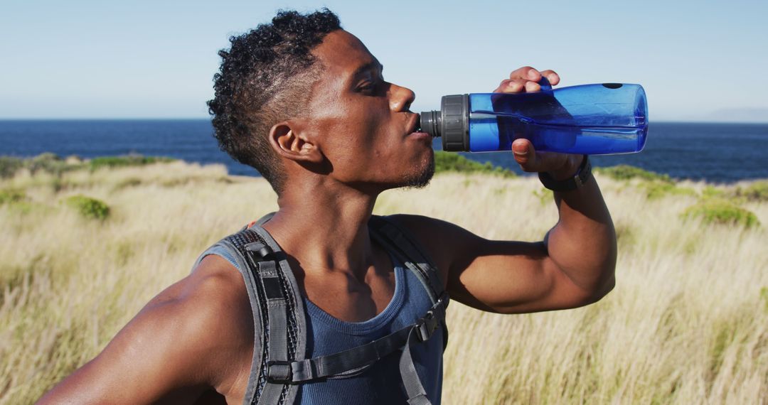 Young Man Drinking Water During Outdoor Hike by the Ocean - Free Images, Stock Photos and Pictures on Pikwizard.com