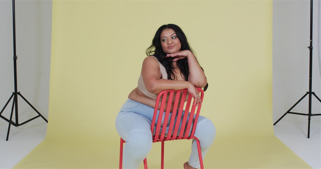 Confident Woman Seated on Red Chair in Creative Studio Setting