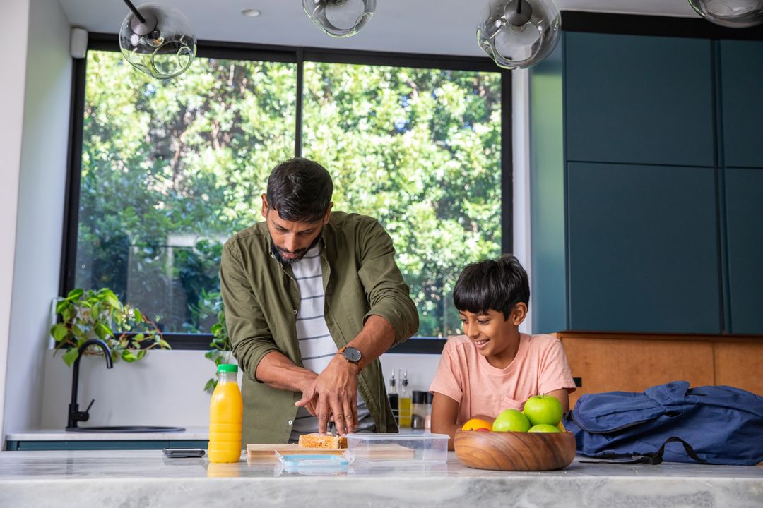 Father Slicing Bread with Son Observing in Modern Kitchen
