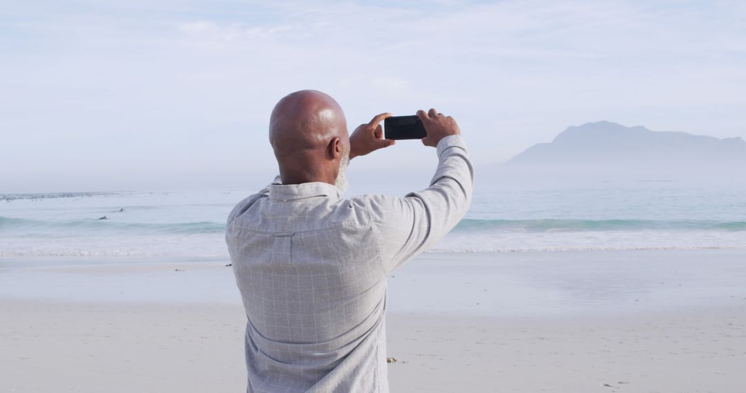 Man Taking Photo of Ocean Scene with Smartphone on Beach - Free Images, Stock Photos and Pictures on Pikwizard.com